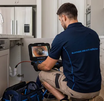 Plumber clearing a blocked toilet in a Ashbury bathroom